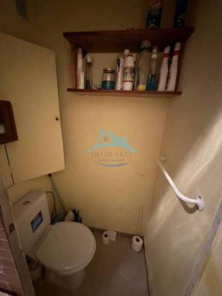 Badezimmer mit Toilette und Regal für Reinigungsmittel in einer 3-Zimmer-Wohnung.