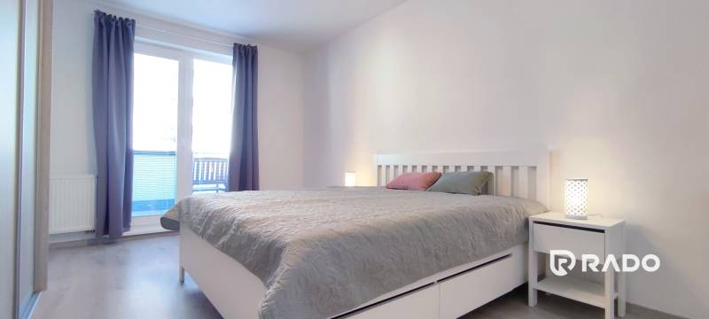 Schlafzimmer in einer 2-Zimmer-Wohnung mit hellen Möbeln und einem Boden in Holzoptik.