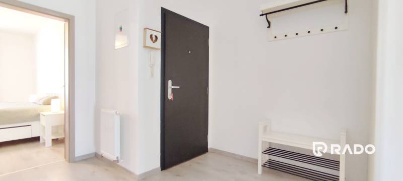 Der Eingangsflur mit hellen Wänden und einem Boden in Holzoptik führt ins Schlafzimmer.