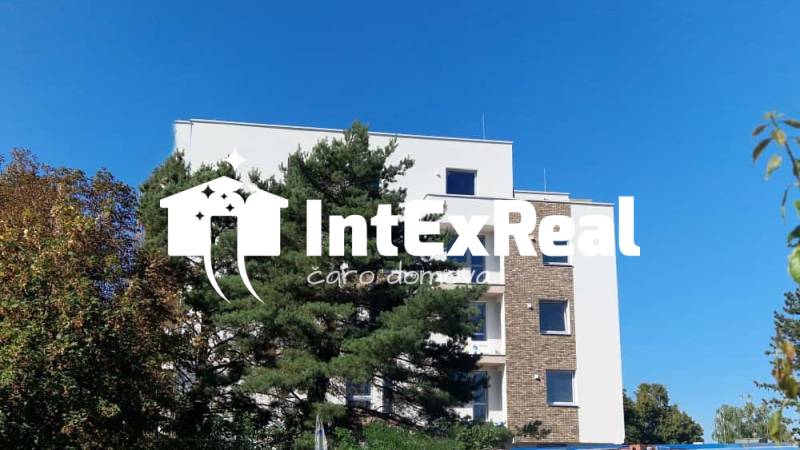 Das Gebäude in der Športová-Straße in Galanta, umgeben von Bäumen, mit klarem Himmel im Hintergrund.