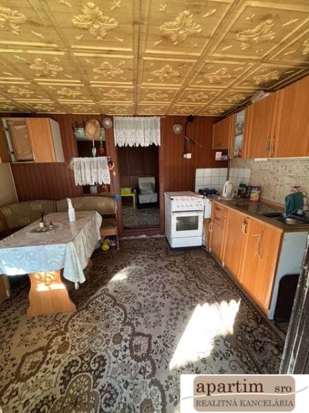 Eine Küche mit älteren Möbeln, ein Boden mit Holzdekor, sichtbarer Essbereich.