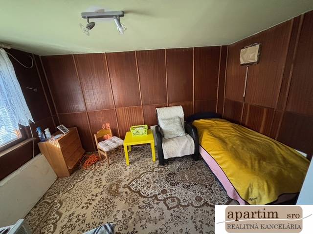 Ein Zimmer mit Stühlen, einem Bett, einem Schrank und einem dekorativen Teppich in den Gärten.