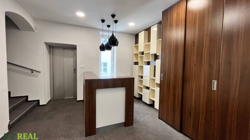 Büros mit Holzelementen, Aufzug, moderner Beleuchtung und dunklem Boden mit Holzdekor.