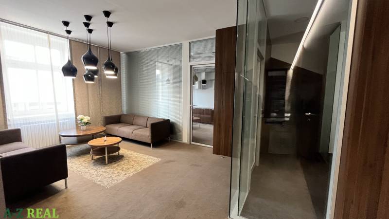 Büros mit Sofas und Couchtisch, Boden mit Holzdekor, Glaswände.