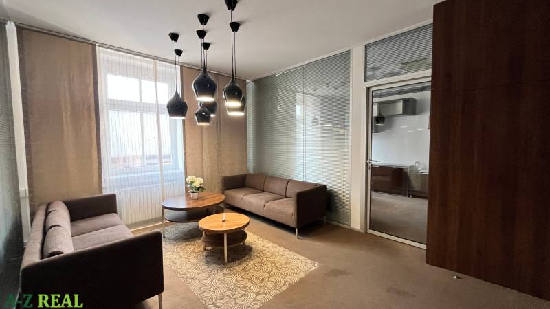 Büros mit bequemen Sofas, einem runden Tisch und interessanter Beleuchtung an der Decke.