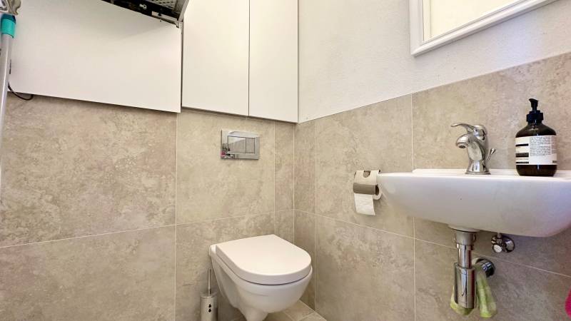 Badezimmer mit Toilette in einer 3-Zimmer-Wohnung, Waschbecken und Aufbewahrungsschränken.