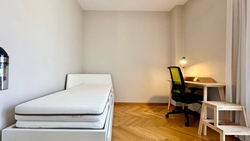 Schlafzimmer in einer 3-Zimmer-Wohnung mit Bett, Schreibtisch und Holzboden.