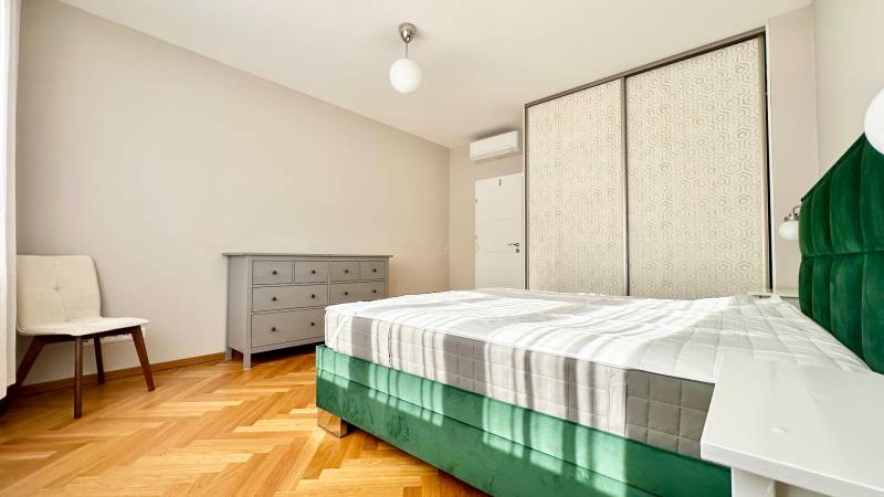 Helles Schlafzimmer mit Bett, Schrank und Boden in Holzoptik in einer 3-Zimmer-Wohnung.