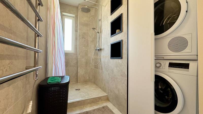 Badezimmer einer 3-Zimmer-Wohnung mit Waschmaschine, Wanddusche und Heizkörper mit Handtüchern.