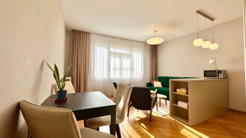 Wohnzimmer mit Holzdekorboden, grünem Sofa und Esstisch in einer 3-Zimmer-Wohnung.