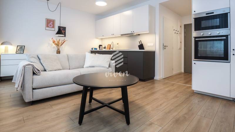 Wohnzimmer mit Küchenzeile in einer Einzimmerwohnung, Boden mit Holzdekor.