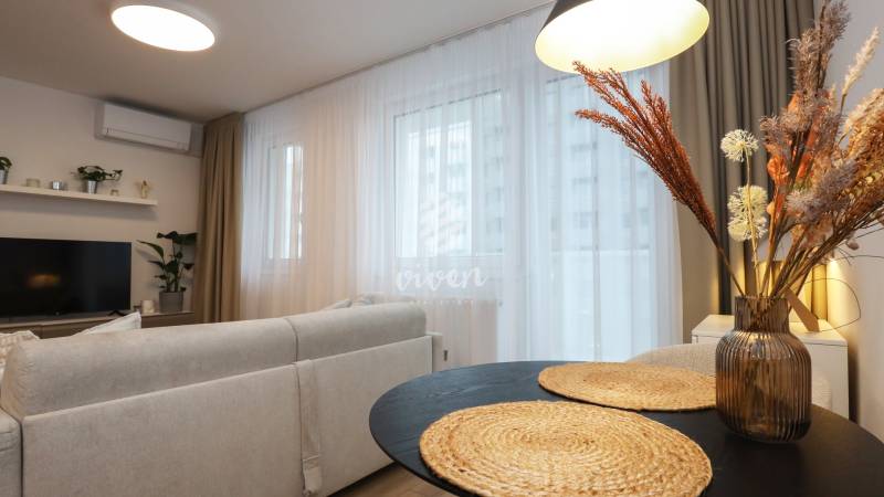 Obývací pokoj v jednopokojovém bytě s pohodlným posezením a dekorativními prvky.