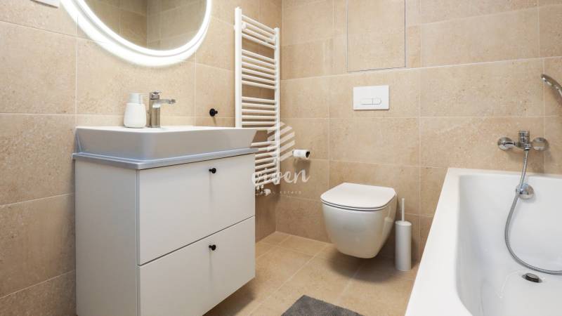 Badezimmer in einer Einzimmerwohnung mit Waschtisch, WC und Badewanne.