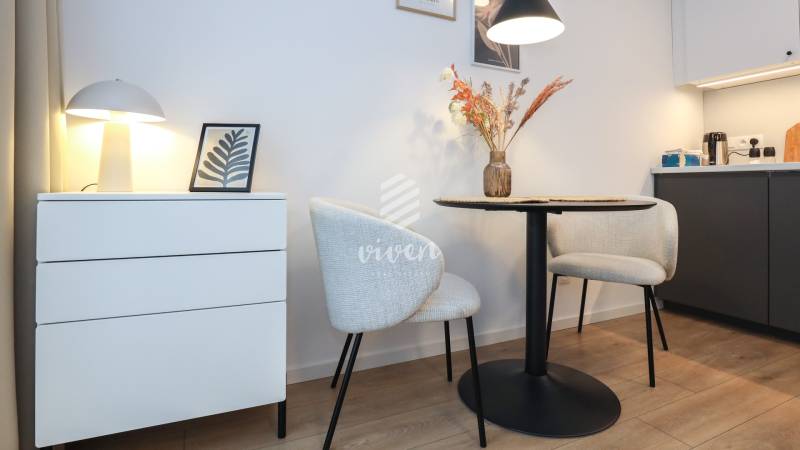 Einzimmerwohnung mit dekorativen Stühlen, Tisch und Lampe auf einem Boden mit Holzdekor.