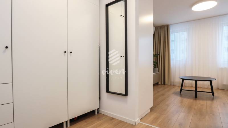 Möbel in einer Einzimmerwohnung mit Holzboden und einem schwarzen Tisch.