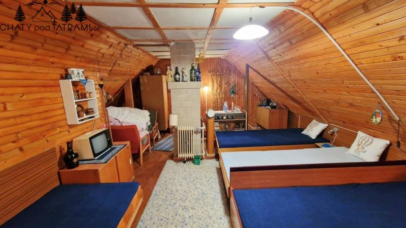 Ein Innenraum einer Hütte aus Holz mit drei Betten und einem Fernseher im traditionellen Stil.