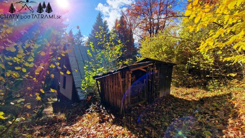 Eine Hütte im Dorf Bystrá in Tále, umgeben von herbstlicher Natur, mit einem Unterstand im Wald.