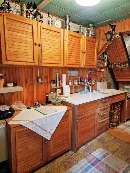 Eine Küche in einer Hütte mit Holzschränken und einer weißen Arbeitsplatte, gemütliche Atmosphäre.