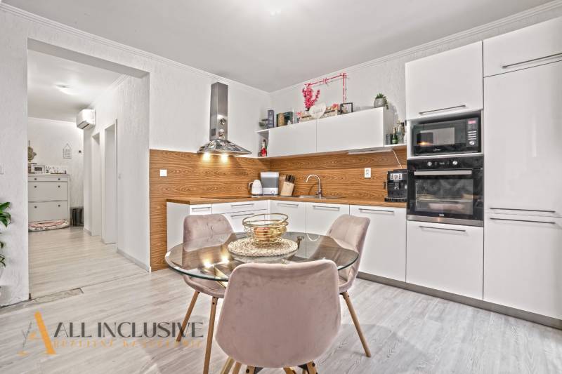 Küche in einer 3-Zimmer-Wohnung mit weißen Schränken, Boden in Holzoptik und Esstisch.