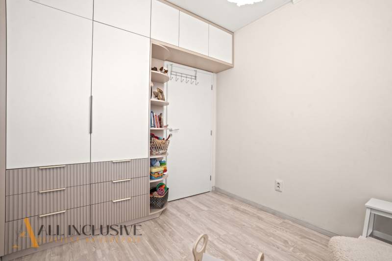 Kinderzimmer mit weißem Schrank und offenen Regalen in einer 3-Zimmer-Wohnung.