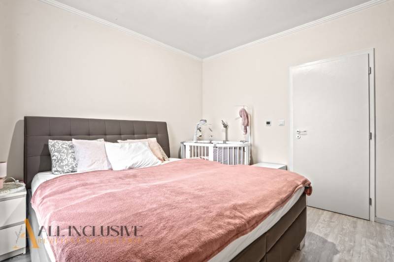 Schlafzimmer in einer 3-Zimmer-Wohnung mit einem bequemen Bett und einem Kinderbett.