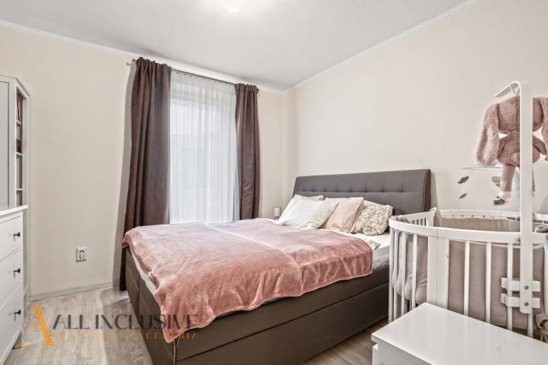 Schlafzimmer in einer 3-Zimmer-Wohnung mit einem Bett und einem Kinderbett, Boden mit Holzdekor.