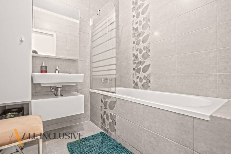 Badezimmer in einer 3-Zimmer-Wohnung mit Duschwanne, Waschbecken und dekorativen Fliesen an den Wänden.