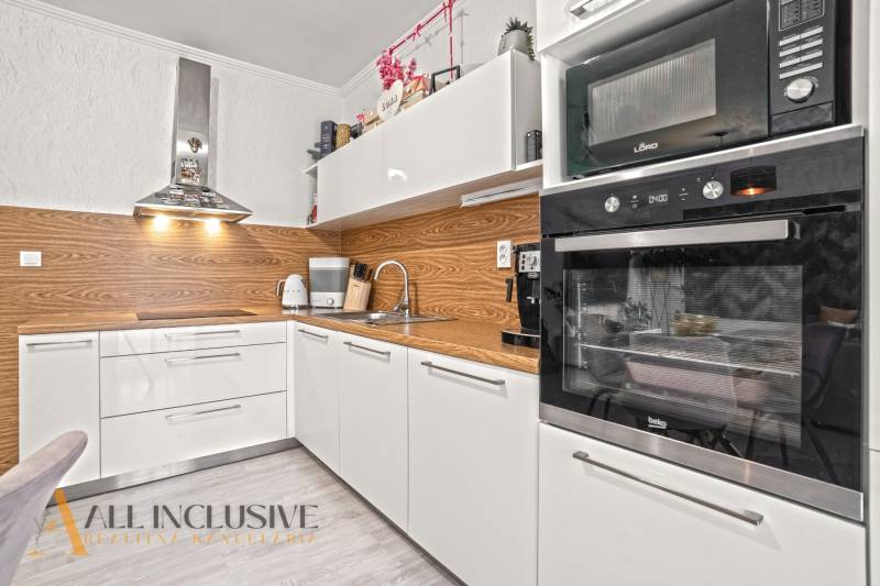 Moderne Küche in einer 3-Zimmer-Wohnung mit weißen Schränken und Holzboden.