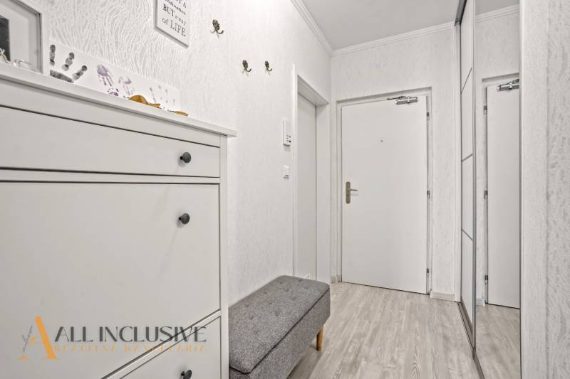 Der Flur in der 3-Zimmer-Wohnung mit weißen Möbeln und einem Boden in Holzoptik.