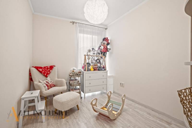 Kinderzimmer in einer 3-Zimmer-Wohnung mit einem bequemen Sessel und Spielzeug, Boden mit Holzdekor.