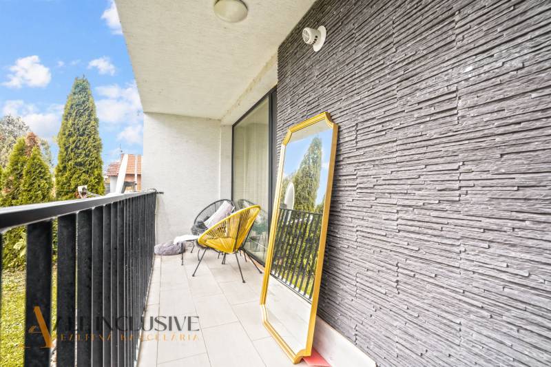 Der Balkon einer 3-Zimmer-Wohnung mit einem dekorativen Spiegel und einem bequemen Sessel.