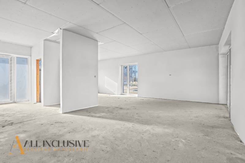 Ein leerer Innenraum in einem Einfamilienhaus mit weißen Wänden und großen Fenstern.