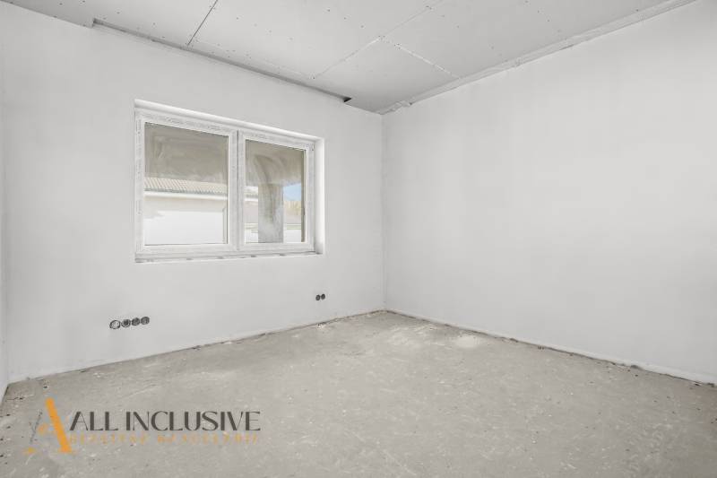 Ein Bauzimmer in einem Einfamilienhaus mit Fenster und unfertigem Boden, bereit zur Fertigstellung.