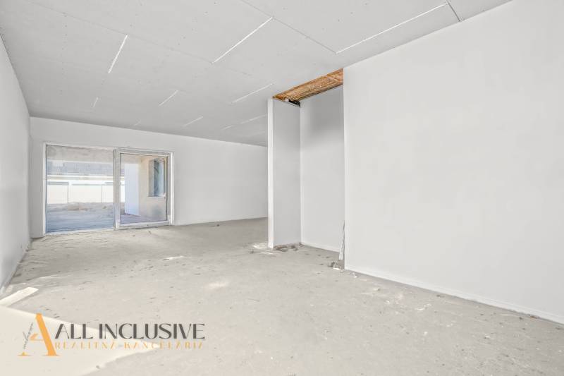 Ein geräumiger Raum in einem Einfamilienhaus mit unfertigem Boden und einem großen Fenster.