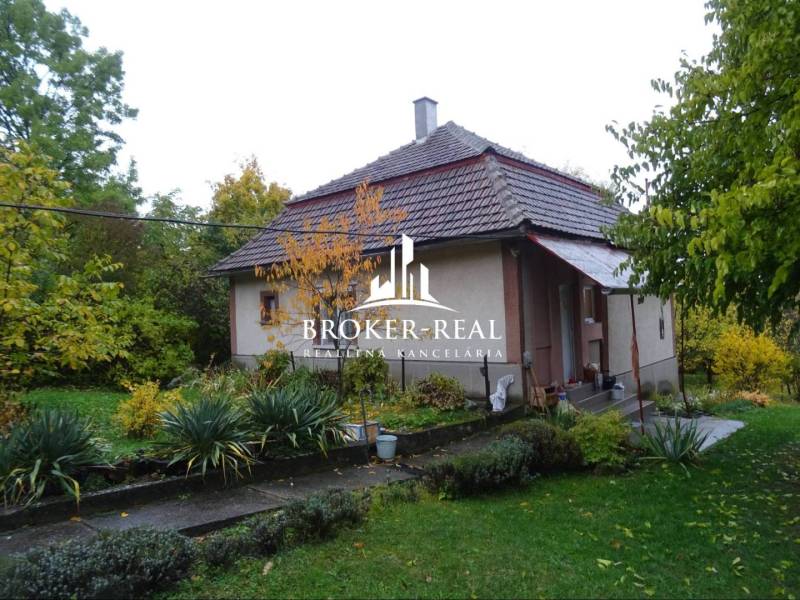 Ein Einfamilienhaus in Fony mit einem großen Garten, umgeben von Grün und Bäumen.