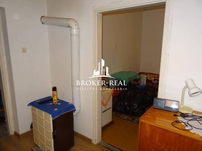 Innenraum eines Einfamilienhauses mit Heizkörper, Möbeln und einem Boden in Holzoptik.