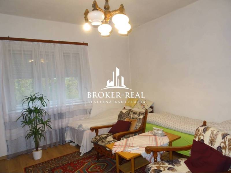 Gemütliches Zimmer in einem Einfamilienhaus mit Sesseln, Betten und einem Boden in Holzoptik.