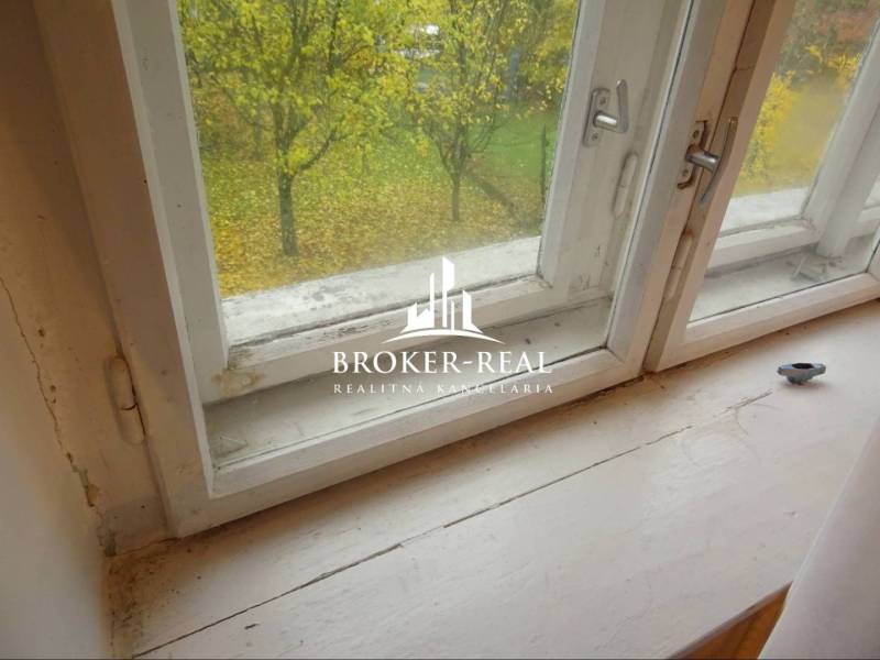 Blick aus dem Fenster in einem Einfamilienhaus mit Aussicht auf den Herbstgarten und einen Baum.