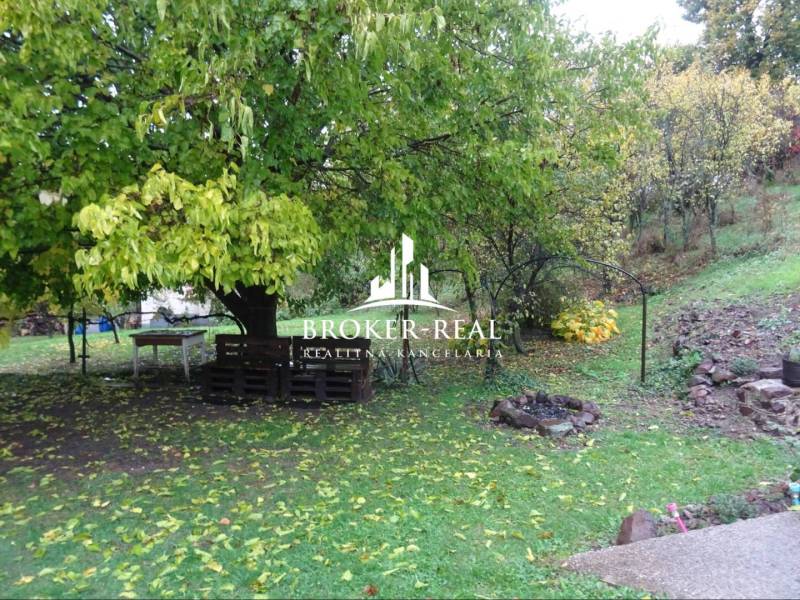 Garten bei einem Einfamilienhaus in Fony, mit Sitzgelegenheiten aus Paletten und einer Feuerstelle.