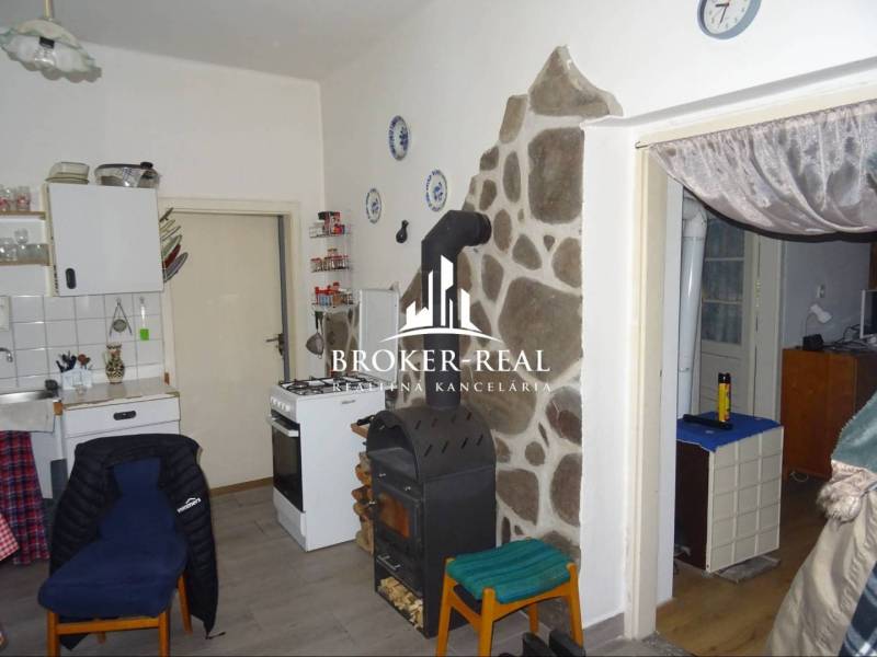 Eine Küche in einem Einfamilienhaus mit einem Herd, einem Ofen und einer Steinverkleidung an der Wand.