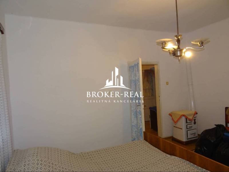 Schlafzimmer in einem Einfamilienhaus mit einfacher Einrichtung und Retro-Heizung.