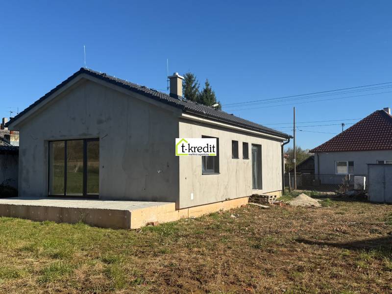 Ein Einfamilienhaus in Tesárske Mlyňany mit einer unverputzten Fassade und einer Betonterrasse.