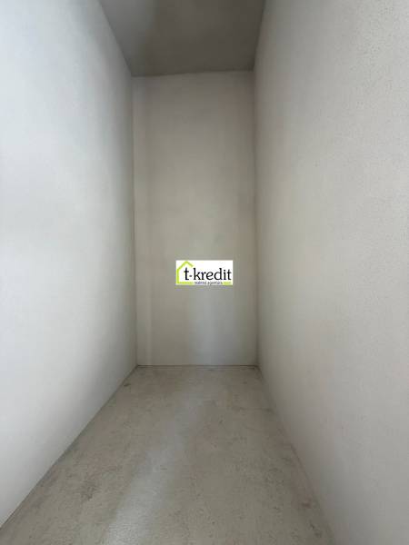 Ein enger, leerer Innenraum eines Einfamilienhauses mit Betonboden und weißen Wänden.