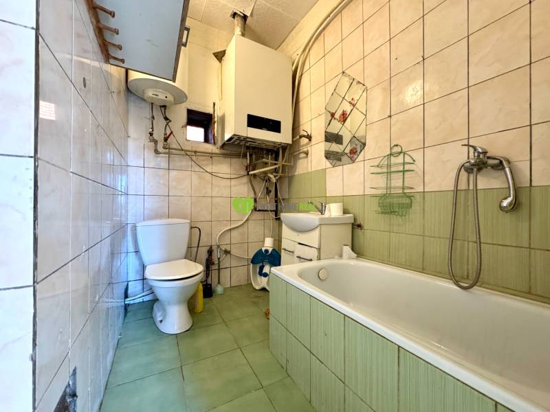 Ein Badezimmer in einem Einfamilienhaus mit einer Badewanne, einem Waschbecken, einer Toilette und Fliesen mit Farbkontrast.