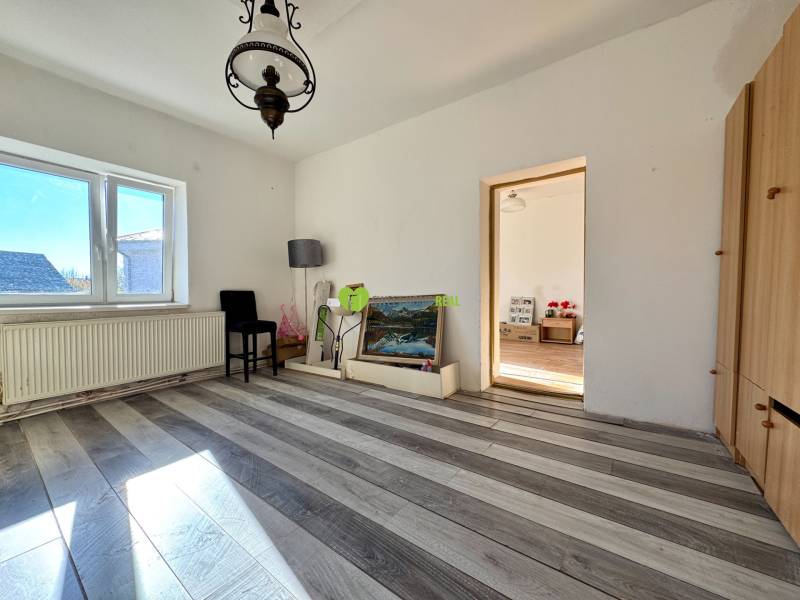 Ein Zimmer in einem Einfamilienhaus mit einer Lampe, einem Bild und einem Boden mit Holzdekor.