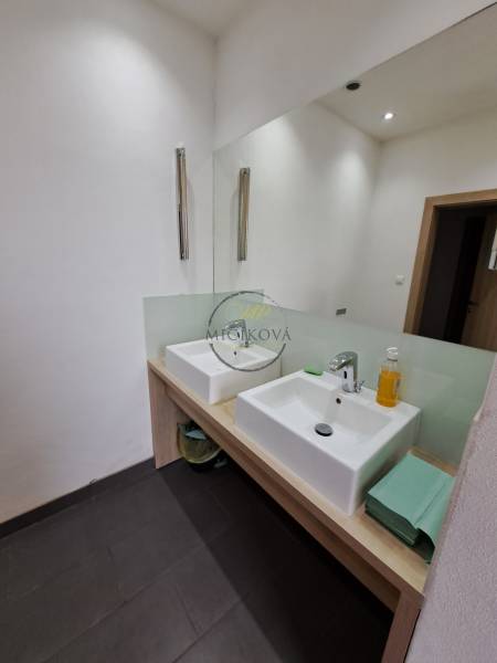 Doppelwaschbecken im Badezimmer eines Büros mit weißen Wänden und einem großen Spiegel.