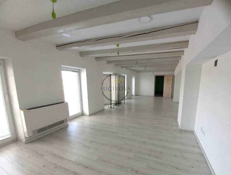 Ein weißes Büro mit Holzdekorboden, dekorativen Balken und hellen Wänden.