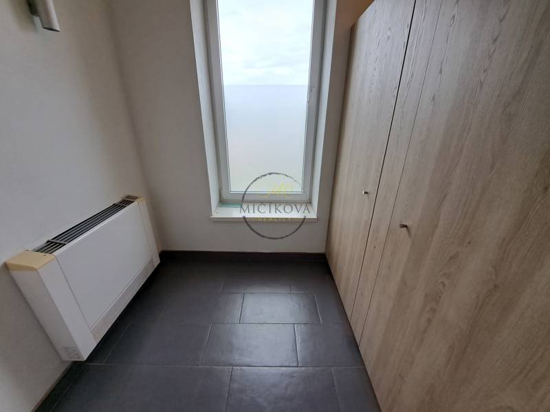 Ein Büro mit Fliesenboden, Stauraum und einem großen Fenster, ohne Möbel.