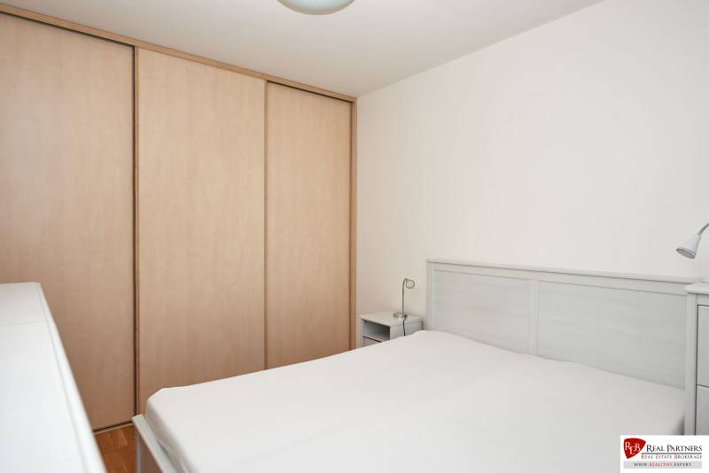 Schlafzimmer in einer 2-Zimmer-Wohnung mit Bett, Schrank und weißen Wänden.