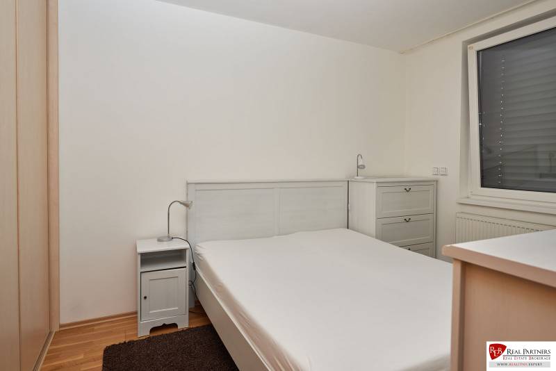 Schlafzimmer in einer 2-Zimmer-Wohnung mit Doppelbett, Nachttisch und Kommode.